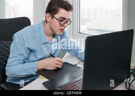 Homme indépendant travaille avec un ordinateur portable et une tablette graphique au bureau à domicile. Lieu de travail indépendant Banque D'Images