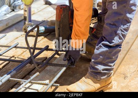 Les ouvriers de la construction utilisent des outils de ficelage de barres d'armature pour fixer les barres d'acier avec des tiges de fil Banque D'Images