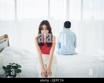 L'anxiété des amoureux du couple asiatique sur le lit. Triste jeune femme et homme assis sur le lit avec des difficultés de relation se sentant triste et pensant en t Banque D'Images