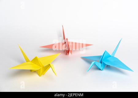 Grues traditionnelles japonaises d'origami en papier sur fond blanc. Oiseaux en papier multicolores. La créativité des enfants. Un symbole de paix. Banque D'Images