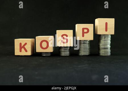 Concept de croissance et de reprise de l'économie boursière en Corée. Indice KOSPI en blocs de bois avec une pile croissante de pièces sur fond noir. Banque D'Images