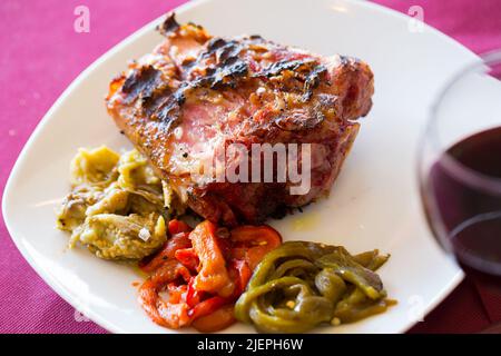 Porte-jarret de porc grillé avec garniture de légumes Banque D'Images