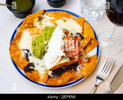 Le maïs Nacho Chips est garni de bœuf haché, de fromage fondu, dans une assiette en céramique dans un restaurant Banque D'Images