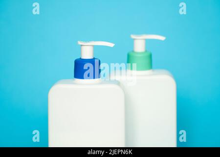 Flacons de shampooing ou de après-shampooing avec pompe à distributeur sur fond bleu. Banque D'Images
