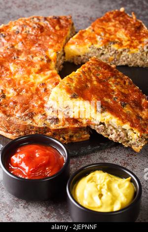 Tarte au cheeseburger avec fromage cheddar de bœuf haché et oignon gros plan sur une plaque d'ardoise sur la table. Verticale Banque D'Images