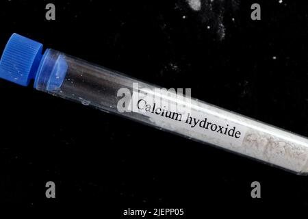 Hydroxyde de calcium dans tube à essai et fond noir Banque D'Images