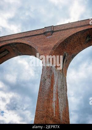 Arches et colonne d'un grand viaduc construit en briques. Un ciel nuageux est en arrière-plan. Banque D'Images