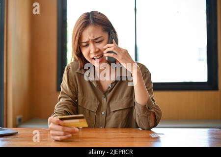 Une jeune femme asiatique furieux et furieux appelant le service de centre d'appels de carte de crédit pour se plaindre de ses problèmes. Paiement en ligne, Internet Banking concept Banque D'Images