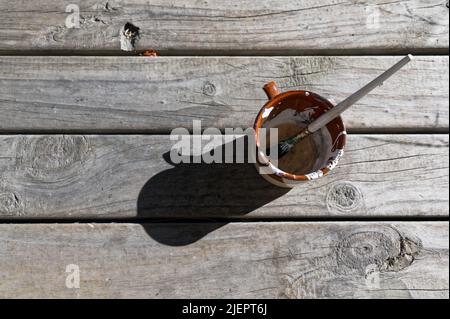 Une petite brosse à peinture, utilisée pour les détails, est assise dans une tasse, peut-être avec des tourelles dans le fond pour le nettoyer. Banque D'Images