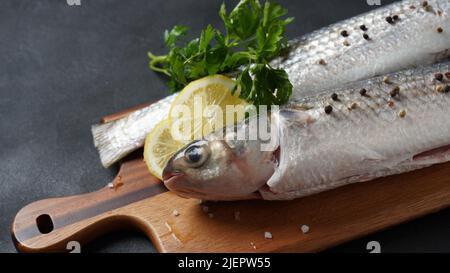 Fruits de mer poisson-mulet frais à la chaux, aux herbes et aux épices sur fond sombre. Banque D'Images