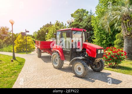Tracteur à équipement spécial avec une remorque dans le parc de la ville, nettoyage et entretien du territoire et des plantes Banque D'Images