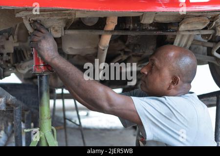 Le mécanicien ouvre le moteur sous la voiture Banque D'Images