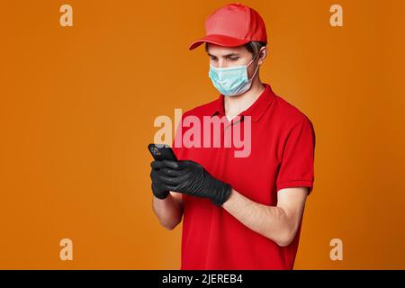 Employé de l'liveur dans un masque facial rouge, vider la boîte en carton Banque D'Images