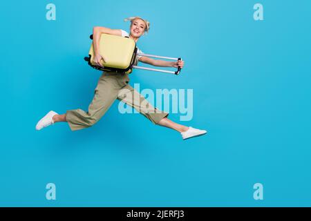 Photo de tout le corps de jeune femme blonde funky saut avec sac porter t-shirt ensemble chaussures isolées sur fond bleu Banque D'Images