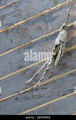 morceau de ficelle abîmé pendant sur le côté de la coque de bateau en bois fraîchement calfeutie Banque D'Images