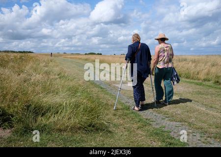 deux personnes marchant le long du chemin côtier bishopstone à la baie de recouvrement, est de kent, royaume-uni juin 2022 Banque D'Images