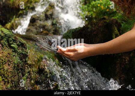 Gros plan portrait d'une femme mains en train de tremper l'eau de la cascade dans la montagne Banque D'Images