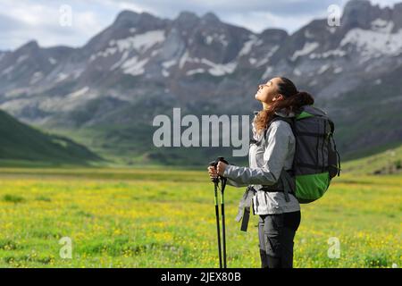 Vue latérale d'un randonneur respirant de l'air frais dans une haute montagne Banque D'Images