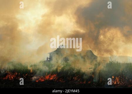 SUMATRA SUD, 28 juin 2022 (Xinhua) -- la fumée du feu de tourbière est vue près de la zone résidentielle dans le village d'Arisan Jaya dans le sud de Sumatra, Indonésie, 28 juin 2022. (Photo de M. Hatta/Xinhua) Banque D'Images