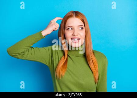 Photo de charmante jeune femme gaie main doigt sur la tête regard vide espace isolé sur fond bleu Banque D'Images