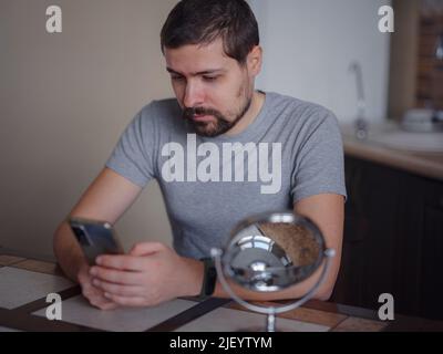 guy vérifiant sa peau. Le jeune homme regardant dans le miroir touche le visage avec le bouton se sent mécontent. Traitement anti-acné de soin de la peau, déséquilibre hormonal, stress, régime alimentaire, problème de peau, concept d'aspect de rétrodiffusion Banque D'Images