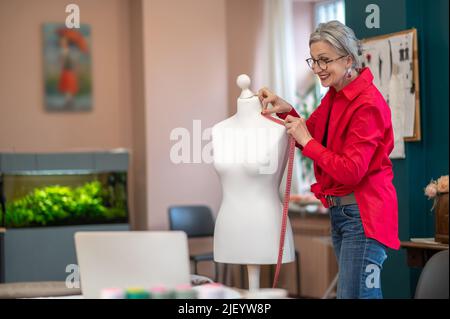 Femme touchant la mesure à l'épaule des mannequins Banque D'Images