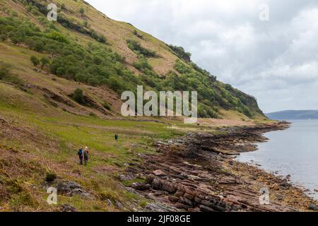 Les gens qui marchent le long de la côte entre Sannox et Lochranza sur l'île d'Arran, en Écosse. Banque D'Images