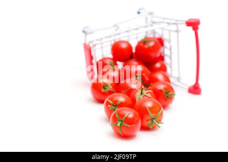 Chariot de supermarché miniature renversé avec tomates cocktail fraîches isolées sur blanc. Banque D'Images