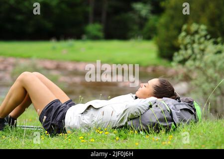 Vue latérale portrait d'un randonneur reposant sur un bord de rivière allongé sur l'herbe Banque D'Images