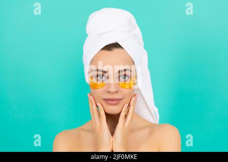 la jeune fille a des taches d'or de collagène pour les yeux sur le visage avec une serviette Banque D'Images