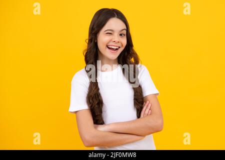 Une adolescente petite fille ferme un œil, se tord et sourit. Concept d'émotions faciales humaines. Geste drôle de visage de clin d'œil. Adolescent heureux, positif et souriant Banque D'Images