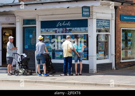 Homme avec une poussette poussette et un couple regardant une fenêtre d'agents immobiliers, pupilles, tenterden, kent, royaume-uni Banque D'Images