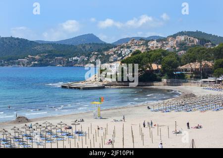 Peguera, Mallorca, Espagne - 05.01.2022: Personnes sur la plage hors saison à Peguera, Majorque. Maisons sur des collines en arrière-plan. Banque D'Images