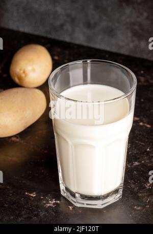 Verre avec lait de pomme de terre de légumes et tubercules de pomme de terre sur la vieille surface en métal rouillé gros plan. Une alimentation naturelle saine. Autre produit de remplacement du lait sans lactose. Banque D'Images