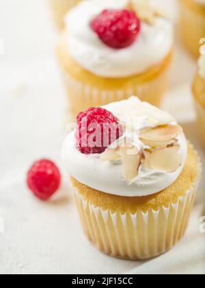 Gros plan. Dessert d'été léger - muffins à la crème, framboises fraîches et amandes. Isolé sur fond blanc. Anniversaire, anniversaire, banquet, picine Banque D'Images