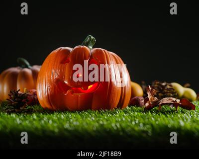 composition mystique. Sur une pelouse verte, une citrouille d'Halloween avec un visage sculpté est illuminée de l'intérieur par une bougie contre un ciel sombre effrayant. Ha Banque D'Images