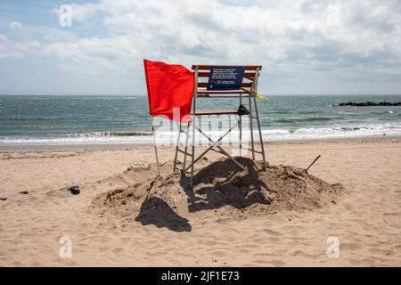 Pas de natation, pas de passage à gué. Drapeau rouge par chaise de maître-nageur sur la plage vide de Coney Island Beach dans le quartier de Brooklyn de New York City, États-Unis d'Amérique Banque D'Images