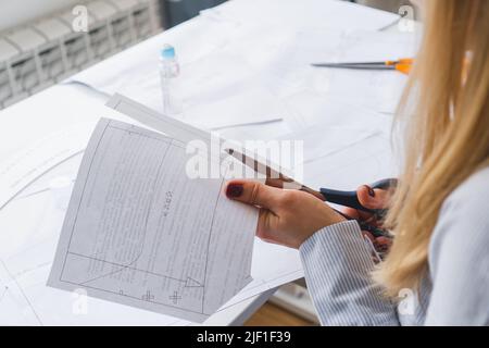 La couturière coupe des motifs de paper pour la robe avec des ciseaux. Développement de conception et création de vêtements Banque D'Images