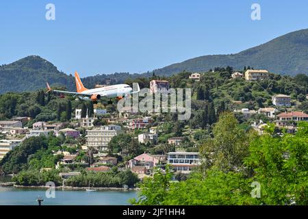 Corfou, Grèce - juin 2022 : Boeing 737 exploité par Sunwing survolant des bâtiments en bord de mer avant d'atterrir à l'aéroport de Corfou. Banque D'Images