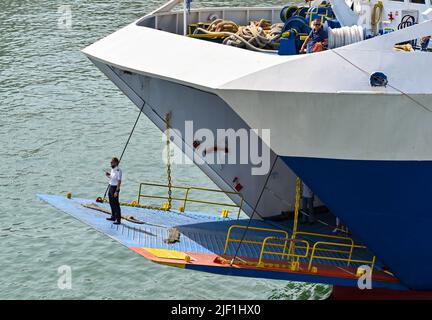 Pirée, Athènes, Grèce - juin 2022 : bureau du navire debout sur la rampe d'accès d'un car ferry guidant le navire dans le quai. Banque D'Images