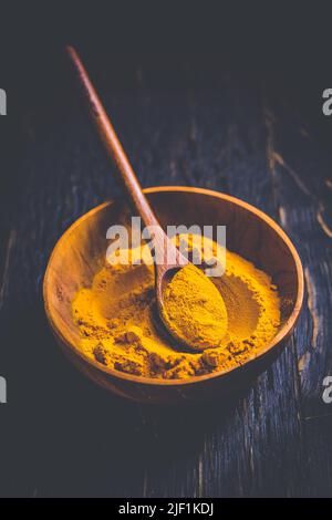 Poudre de curcuma indienne, épice de curcuma dans un petit bol avec une cuillère, poudre de Haldi sur fond de bois Banque D'Images