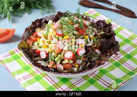 Salade de chou avec bâtonnets de crabe, tomates et maïs servis sur des feuilles de laitue. Gros plan Banque D'Images