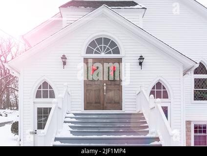 Des serments de Noël sont accrochées aux portes d'entrée de l'église rustique en hiver. Banque D'Images