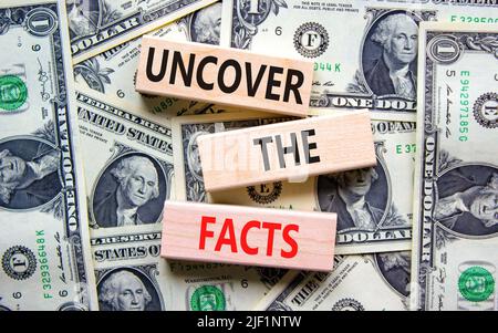 Uncover the facts symbol. Concept words Uncover the facts on wooden blocks on a beautiful background from dollar bills. Business and uncover the facts Banque D'Images