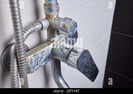 Un jet d'eau dure s'écoule d'un ancien aérateur de robinet. Vieux robinet d'évier de salle de bains contaminé par du calcium et de la saleté Banque D'Images