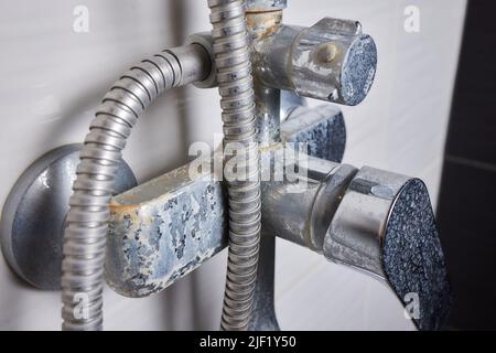 Un jet d'eau dure s'écoule d'un ancien aérateur de robinet. Vieux robinet d'évier de salle de bains contaminé par du calcium et de la saleté Banque D'Images