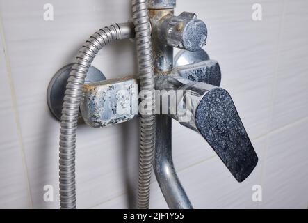 Un jet d'eau dure s'écoule d'un ancien aérateur de robinet. Vieux robinet d'évier de salle de bains contaminé par du calcium et de la saleté Banque D'Images