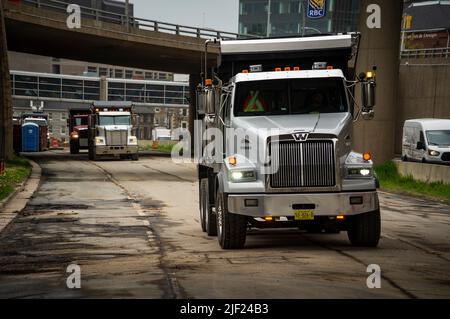 Une ligne de camions à benne tandem sur une chaussée sous un passage de roue. Banque D'Images