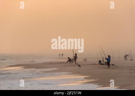 Les gens pêchent dans le golfe du Mexique depuis la plage de Johnson Beach National Seashore en Floride au crépuscule sur 26 mars 2021. Banque D'Images