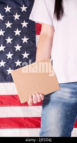 Jeune femme tenant une affiche vierge dans ses mains près. Drapeau américain sur fond. Banque D'Images